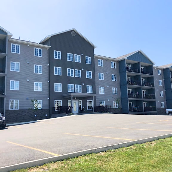 a black car is parked in a parking lot in front of a large apartment building.
