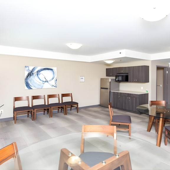 a modern dining room with a large painting on the wall and a kitchen area in the background.