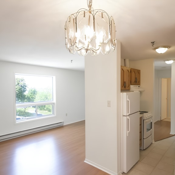 a white kitchen with a large window and a chandelier.