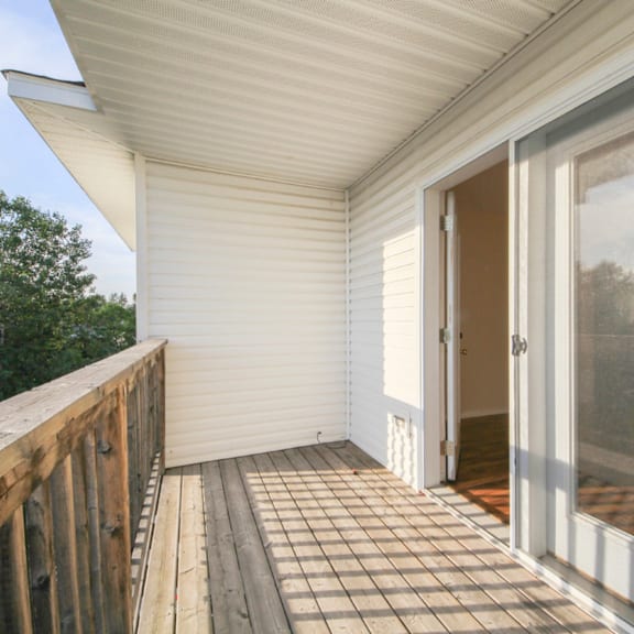 a white screened porch with a wooden railing.