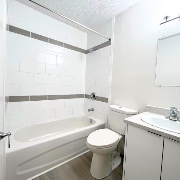 a white bathroom with a toilet, sink, and bathtub.