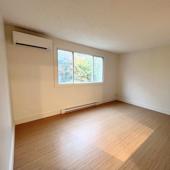 a room with a window and a wall-mounted air conditioner.