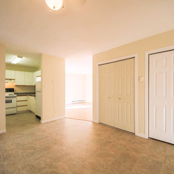 a room with two white doors and a kitchen in the background.
