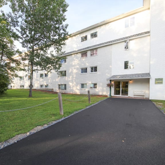 a white building with a black driveway in front.