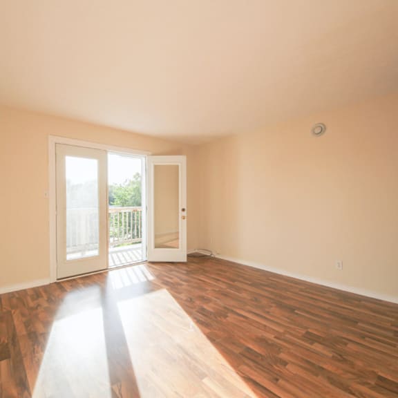 a room with wooden floors and a door leading to a balcony.