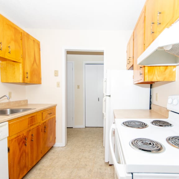 a kitchen with a white stove and wooden cabinets.