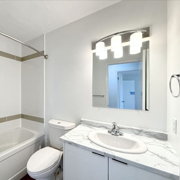 a white bathroom with a toilet, sink, and bathtub.
