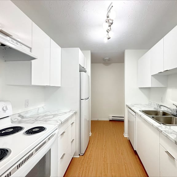 a white kitchen with a stove, refrigerator, and sink.