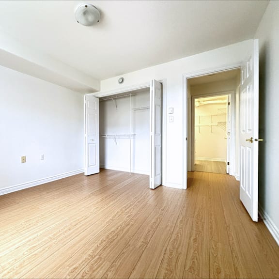 a room with white walls and wooden flooring with a door open to another room.