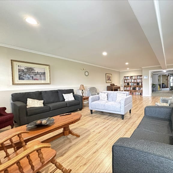 a living room with a grey couch, a wooden coffee table, and a painting on the wall.