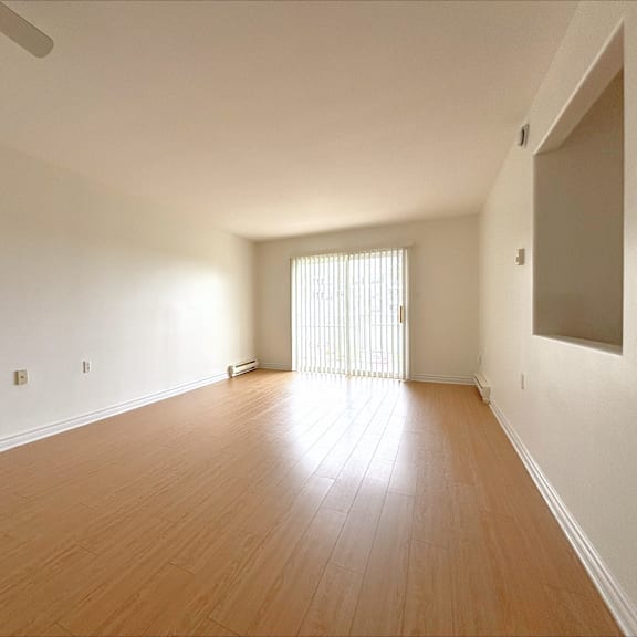 a room with wooden flooring and a window with blinds.
