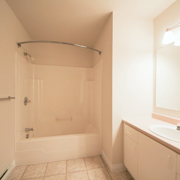 a white bathroom with a tub, sink, and mirror.
