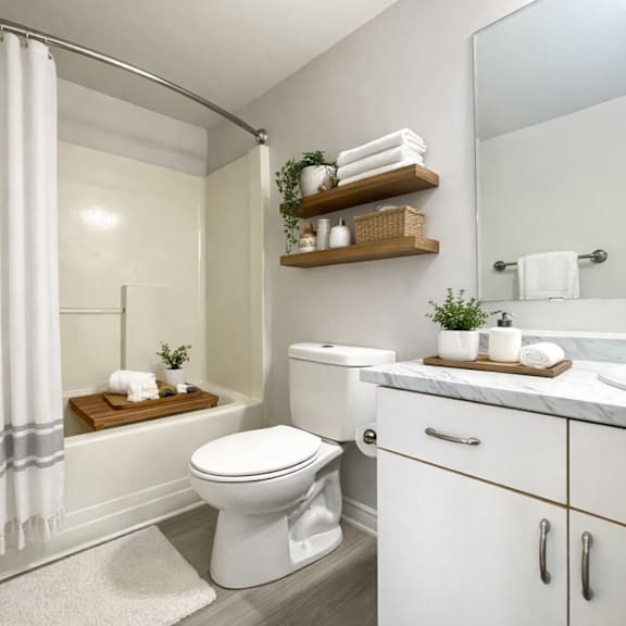 a white toilet sits in a bathroom next to a sink and a shower.