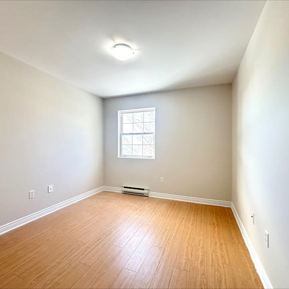 a room with a window and wooden flooring.