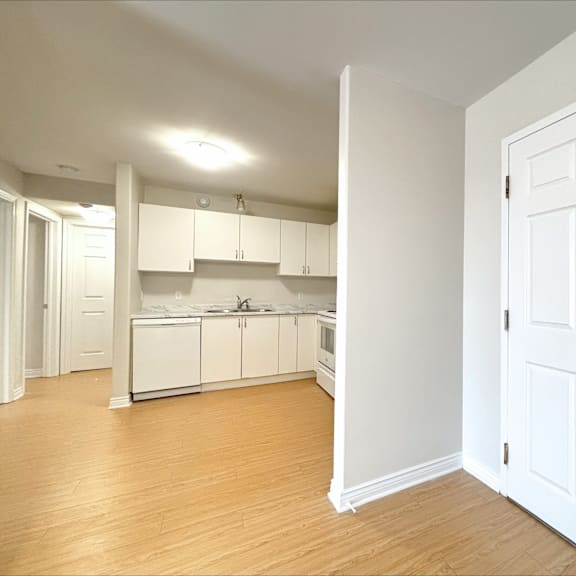 a kitchen with white cabinets and a wooden floor.