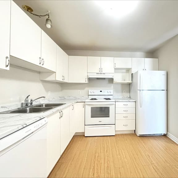 a white kitchen with wooden floors and white appliances.