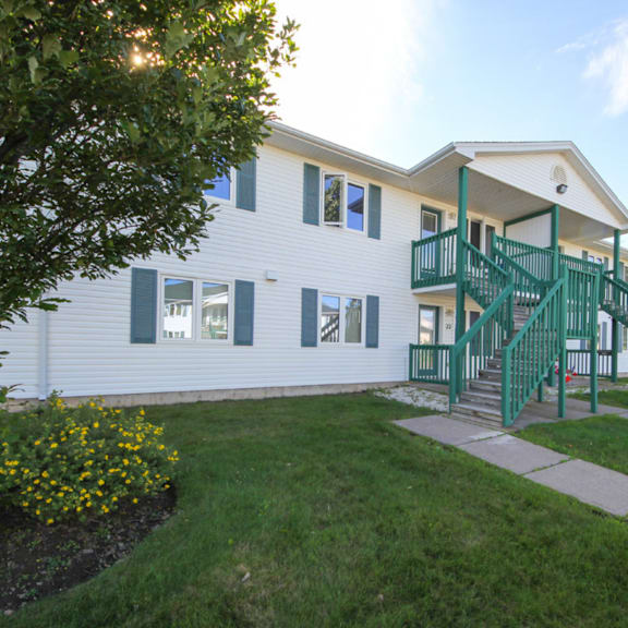 a white house with green railings and a green staircase.
