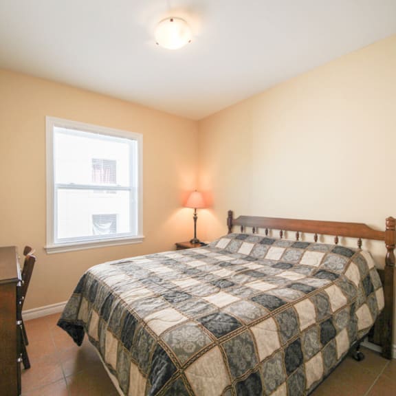 a bedroom with a bed, nightstand, and window.