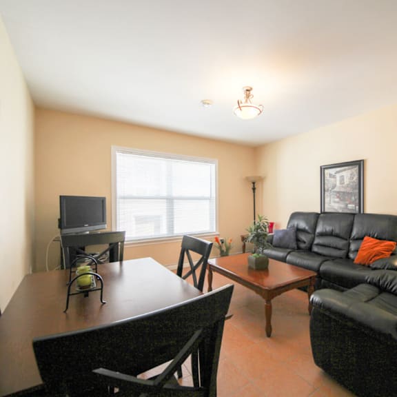 a living room with a black leather couch and a wooden coffee table.