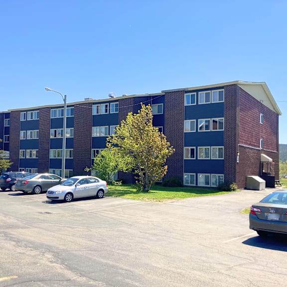 a parking lot with cars and a building in the background.