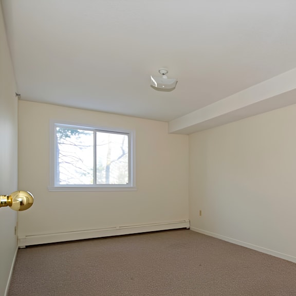 a room with a window and a carpeted floor.
