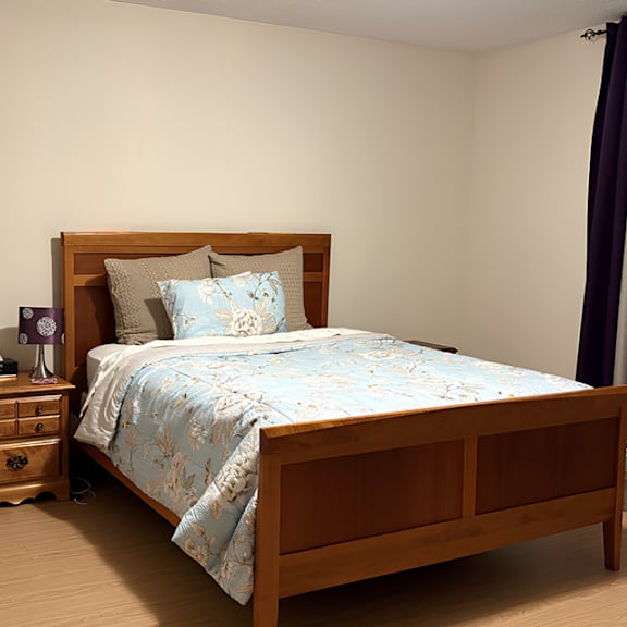 a bed with a wooden headboard and a blue floral comforter.