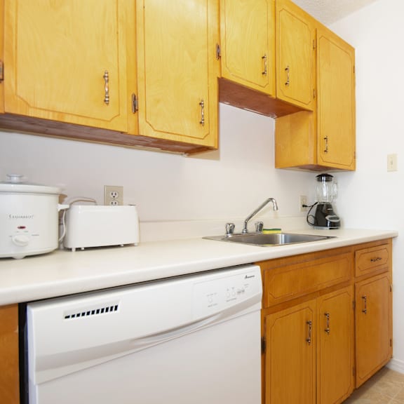 a kitchen with wooden cabinets and a white dishwasher.