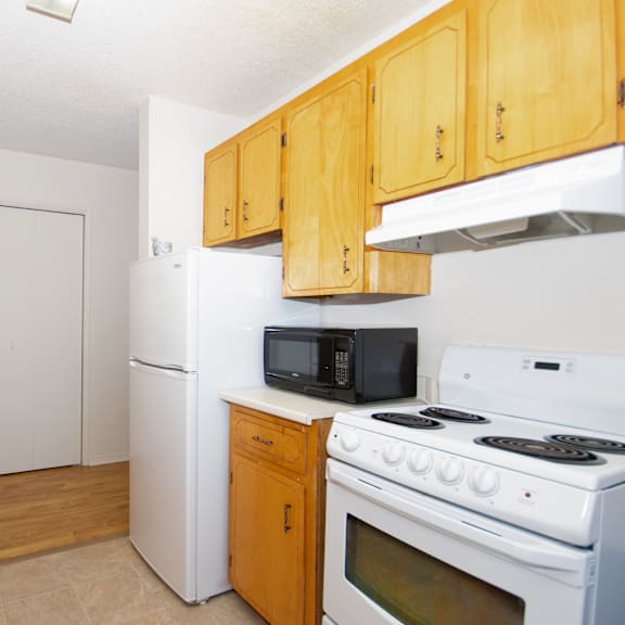 a kitchen with white appliances and wooden cabinets.
