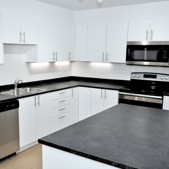a modern kitchen with white cabinets and black countertops.