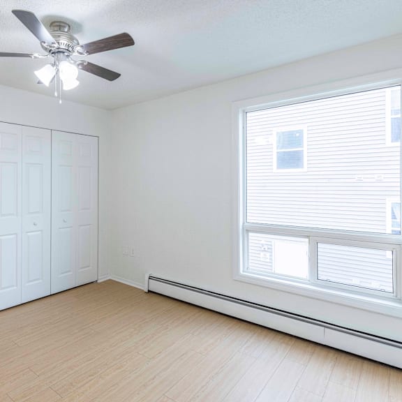 a room with a ceiling fan and a window with blinds.