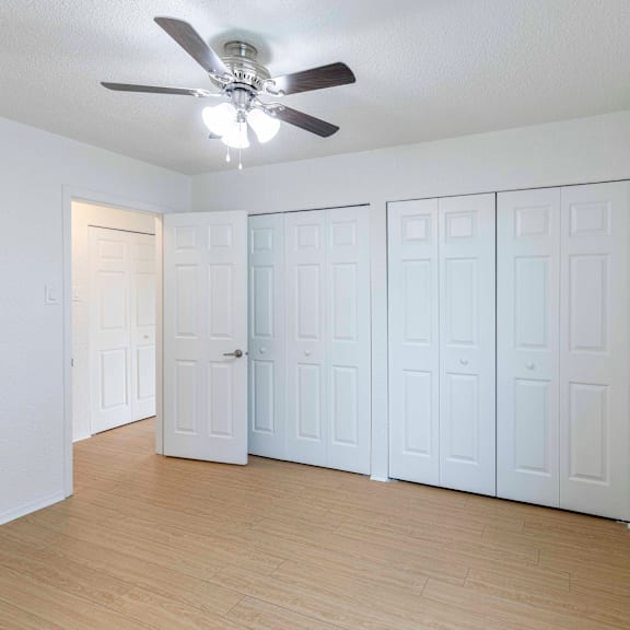 a room with a ceiling fan and white walls.