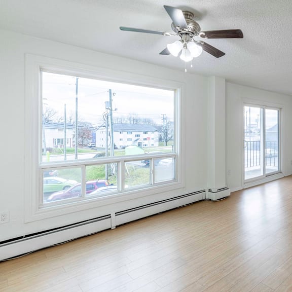 a room with a ceiling fan and large windows.