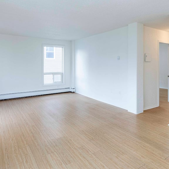 a room with wooden flooring and a window with blinds.