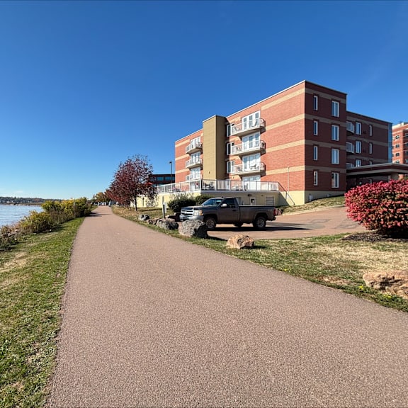 a pathway leads to a large brick building with a truck parked in front.