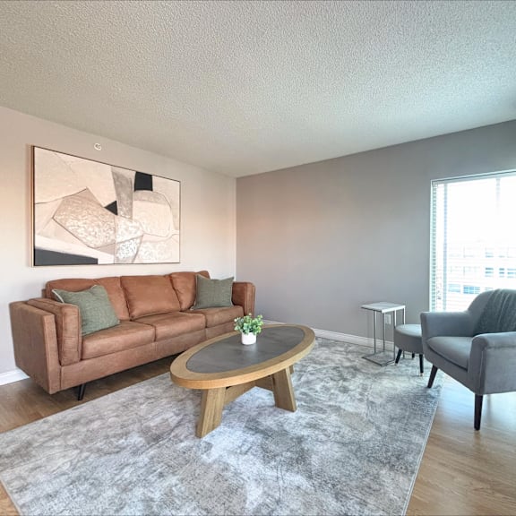 a living room with a brown couch, grey armchair, and a coffee table.