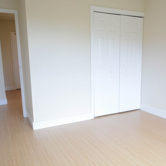 a room with a white door and wooden floor.