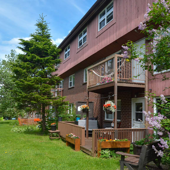a red building with a balcony and a green lawn in front.