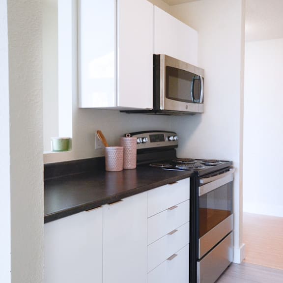 a kitchen with white cabinets and black countertops.