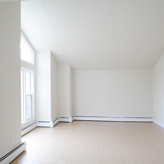 a large empty room with a window on the left side.