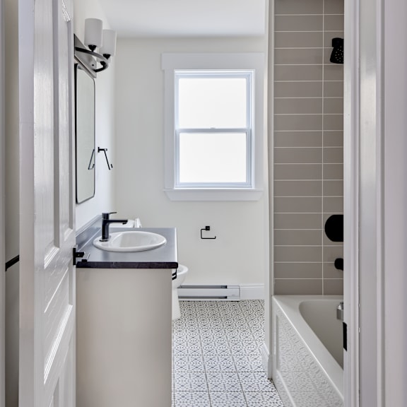 a bathroom with a sink, mirror, and a window.