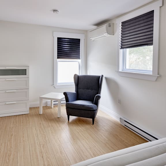 a black chair sits in a white room with a window and a white table.