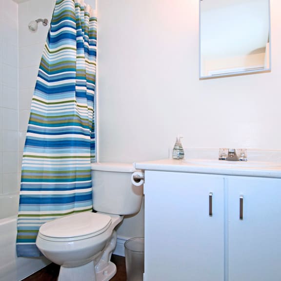 a white toilet with a blue and green striped shower curtain in a bathroom.