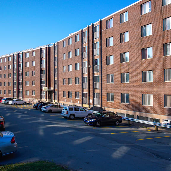 a parking lot in front of a red brick building with cars parked.