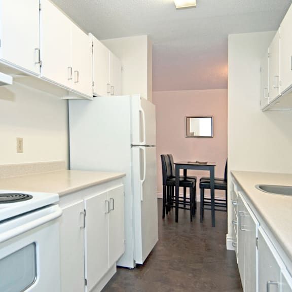 a kitchen with white cabinets and a pink wall.