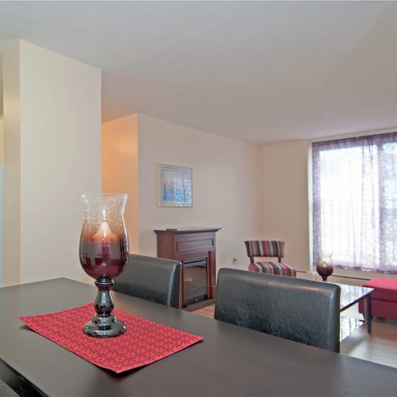 a dining table with a red placemat and a glass vase with a candle inside.