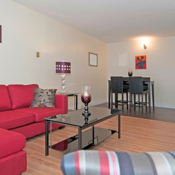 a red couch sits in a living room with a glass table in front of it.