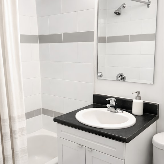 a white bathroom with a black counter top and a white sink.