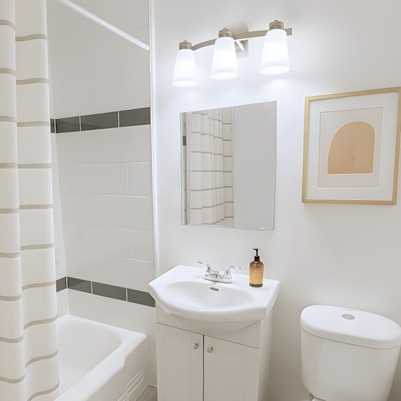 a white bathroom with a toilet, sink, and shower curtain.