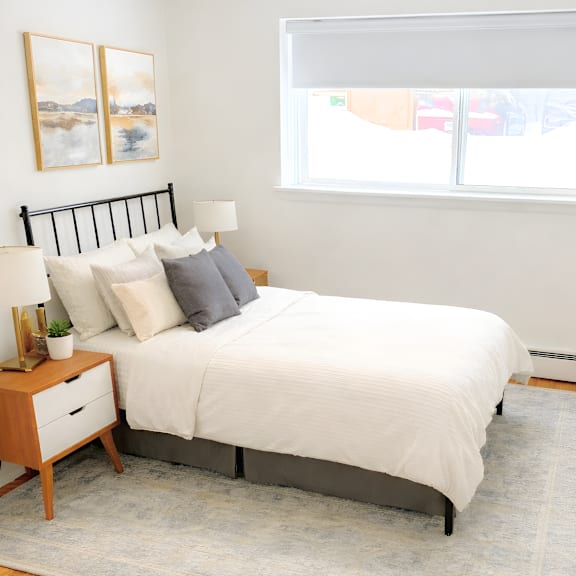 a bedroom with a white bed and a grey rug.