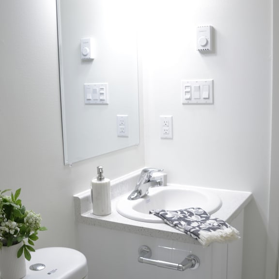 a white bathroom with a toilet, sink, and mirror.